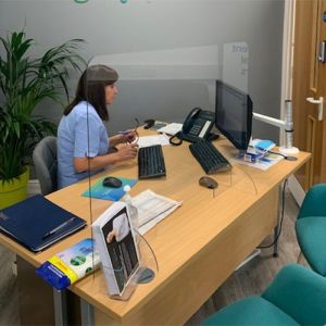 Clear free standing screen added to a reception desk. 